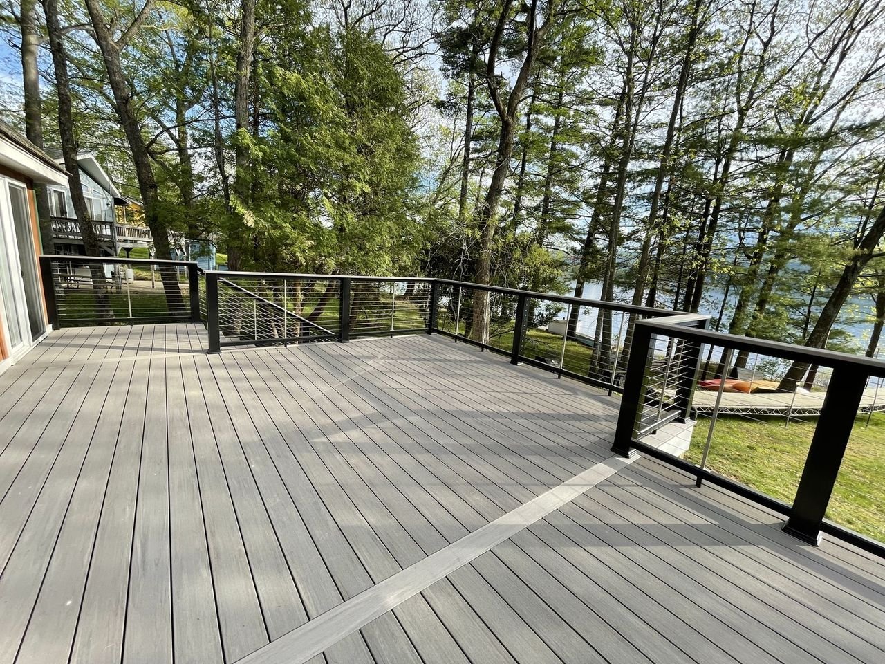 Grey composite deck with black cable railing above the lake