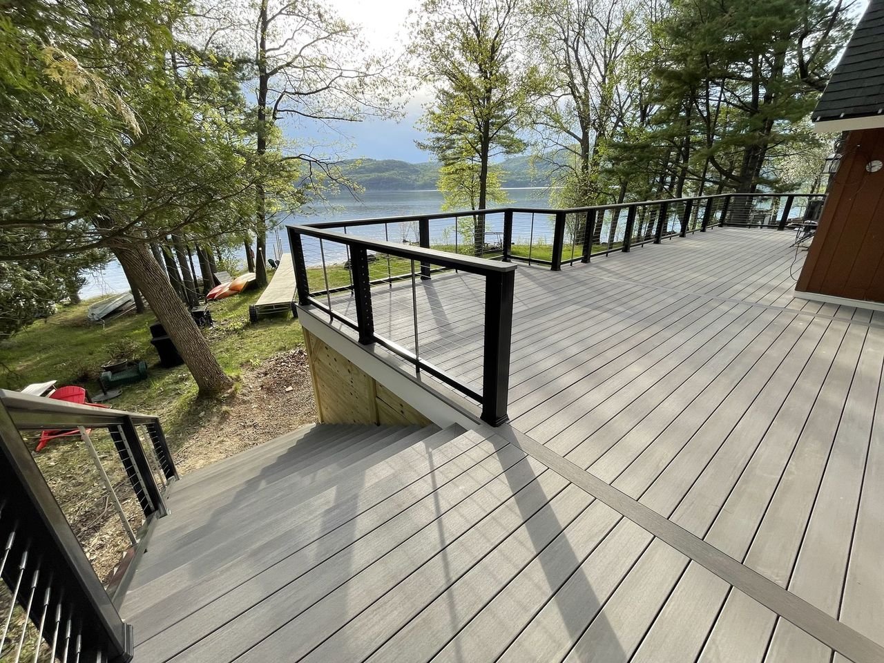 Composite deck wrapping between mature trees down to the water