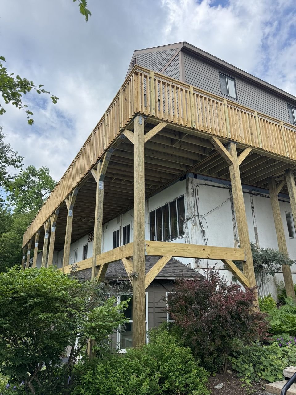 Elevated pressure-treated deck carried on timber posts along the side of a hillside home